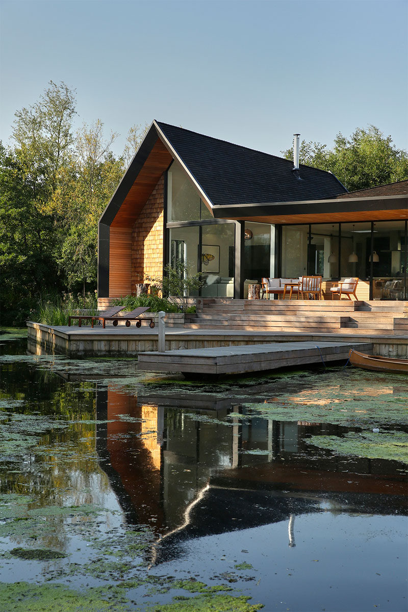 This modern houses sits next to a lagoon and has an outdoor deck with a lounge and sun chairs, as well as a private boat dock.