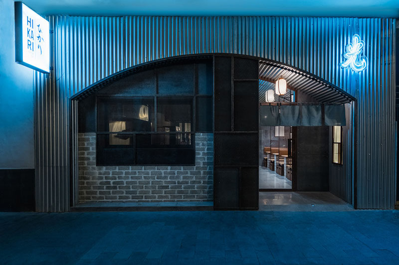 Industrial Interior Design - This Restaurant and bar goes for a warehouse chic style with metal, concrete, and wood. Designed to look like the entrance to a Tokyo tunnel, the facade of this modern restaurant features steel, brick, and neon signage to create an industrial yet inviting exterior.