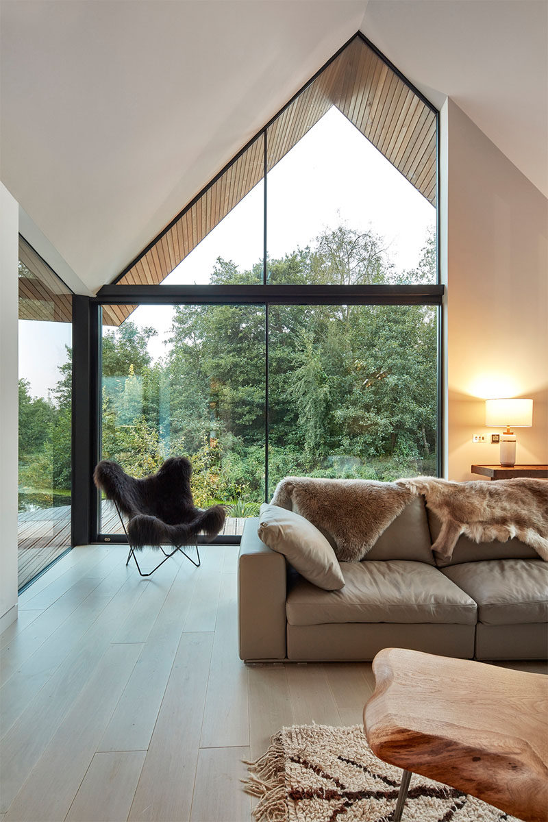 In this double height modern living room, large windows follow the roof line and provide ample natural light to the room.