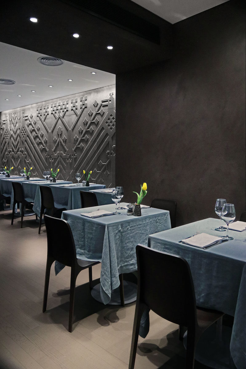 Separating the two dining areas in this modern restaurant,are dark sections of walls made from resin and cement in a dove grey and burnt coffee color that have a matte wax finish.