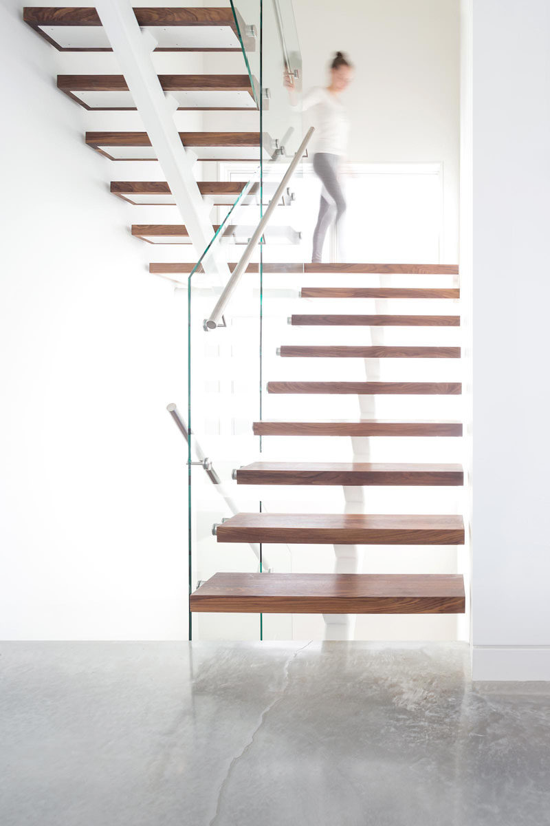 These modern stairs feature walnut treads, while brushed stainless steel handrails are attached to glass balustrades to complete the staircase.