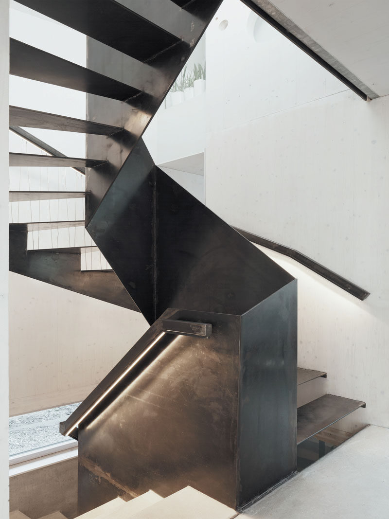 Black steel stairs and handrails continue to lead you up to the upper floor of this modern home.
