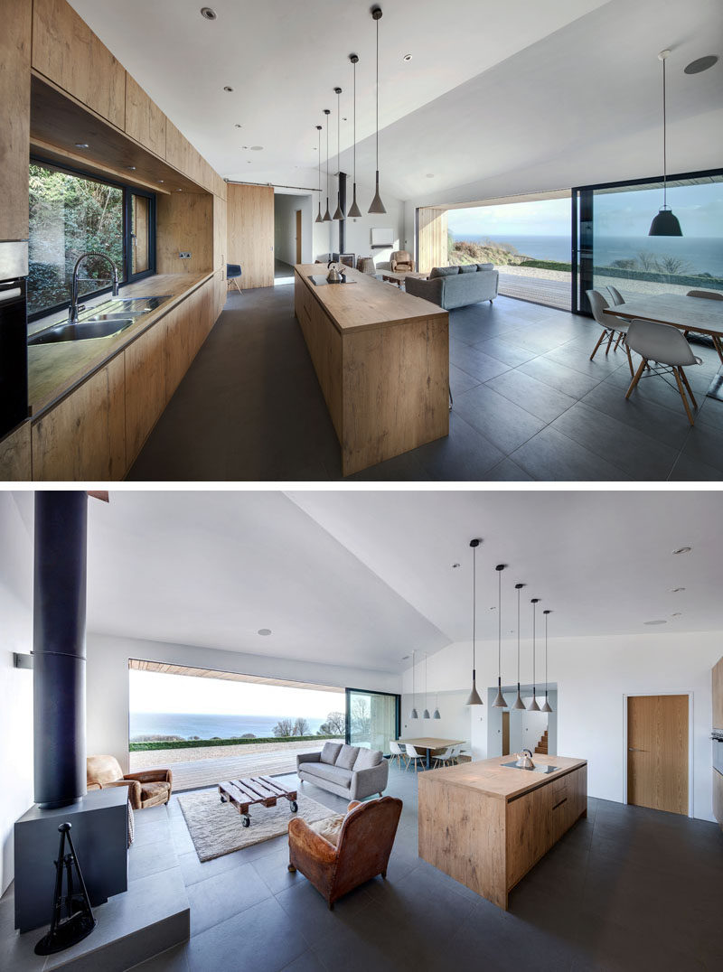 This kitchen brings nature inside with wooden cabinetry and a large window above the sink provides views of the plants outside. A large island with 5 simple pendant lights hanging above, is home to the cooktop and plenty of storage.