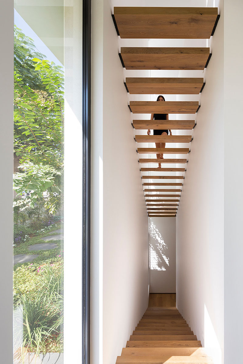 Wooden stairs with black supports lead you to the upper floor of this modern home.