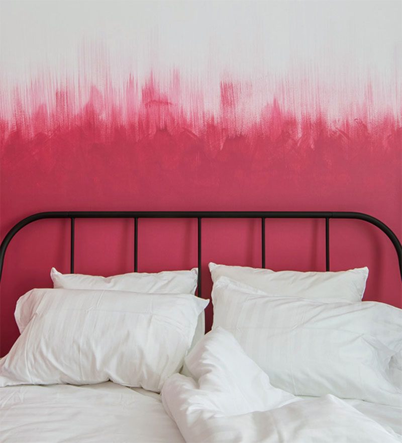 Oksana Dolgopiatova has designed a modern bedroom that features pink and white walls. While the lower part of the wall is solid pink, the top part of the pink blends into the white wall with visible vertical brush strokes creating an ombre effect.