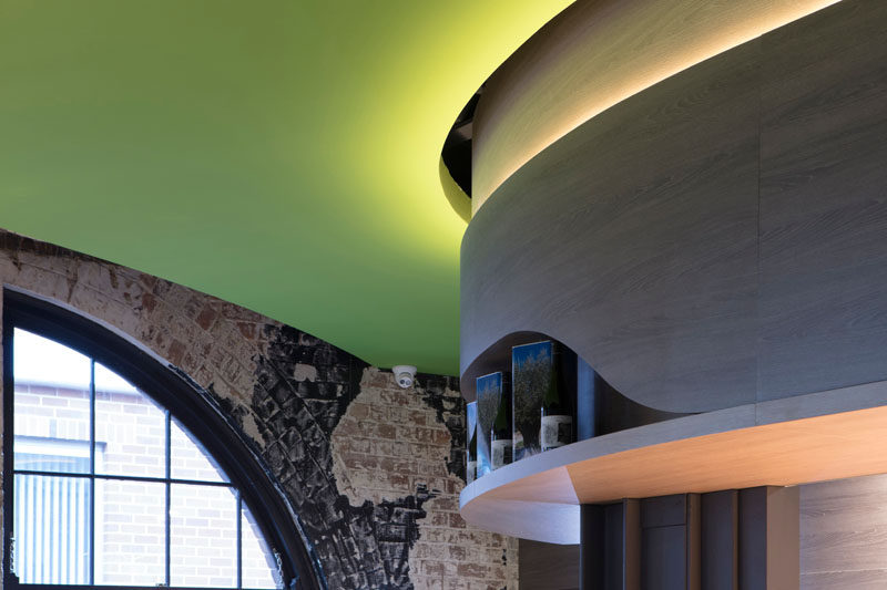 Hidden LED lighting features at the top of these curved wooden panels to highlight the edges of the olive green ceiling.