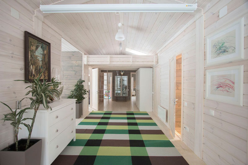 This light wood hallway in this rustic modern house is made from solid pine that's then painted white. A colorful checkered rug leads you to the bedrooms at the end of the hall.