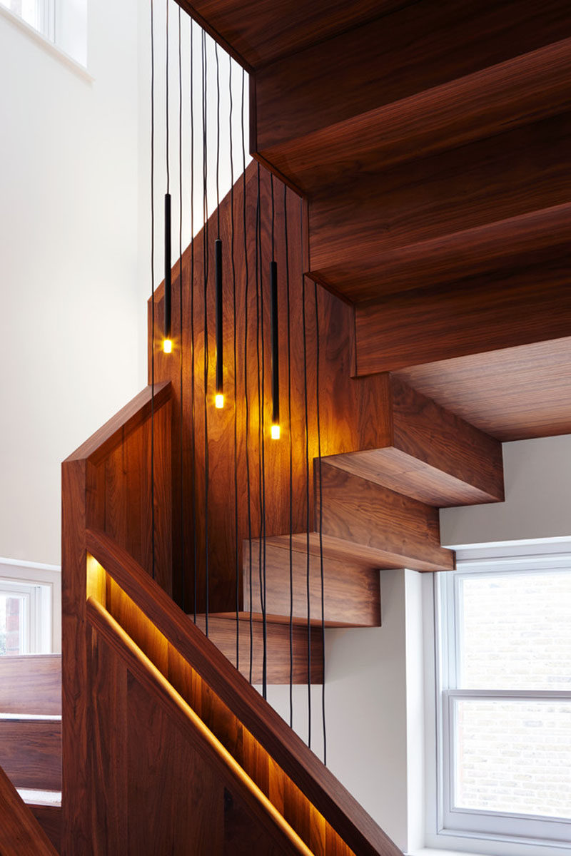 Small pendant lights have been hung down the middle of this staircase with built-in handrails to add more soft lighting and compliment the lights inside the railings.