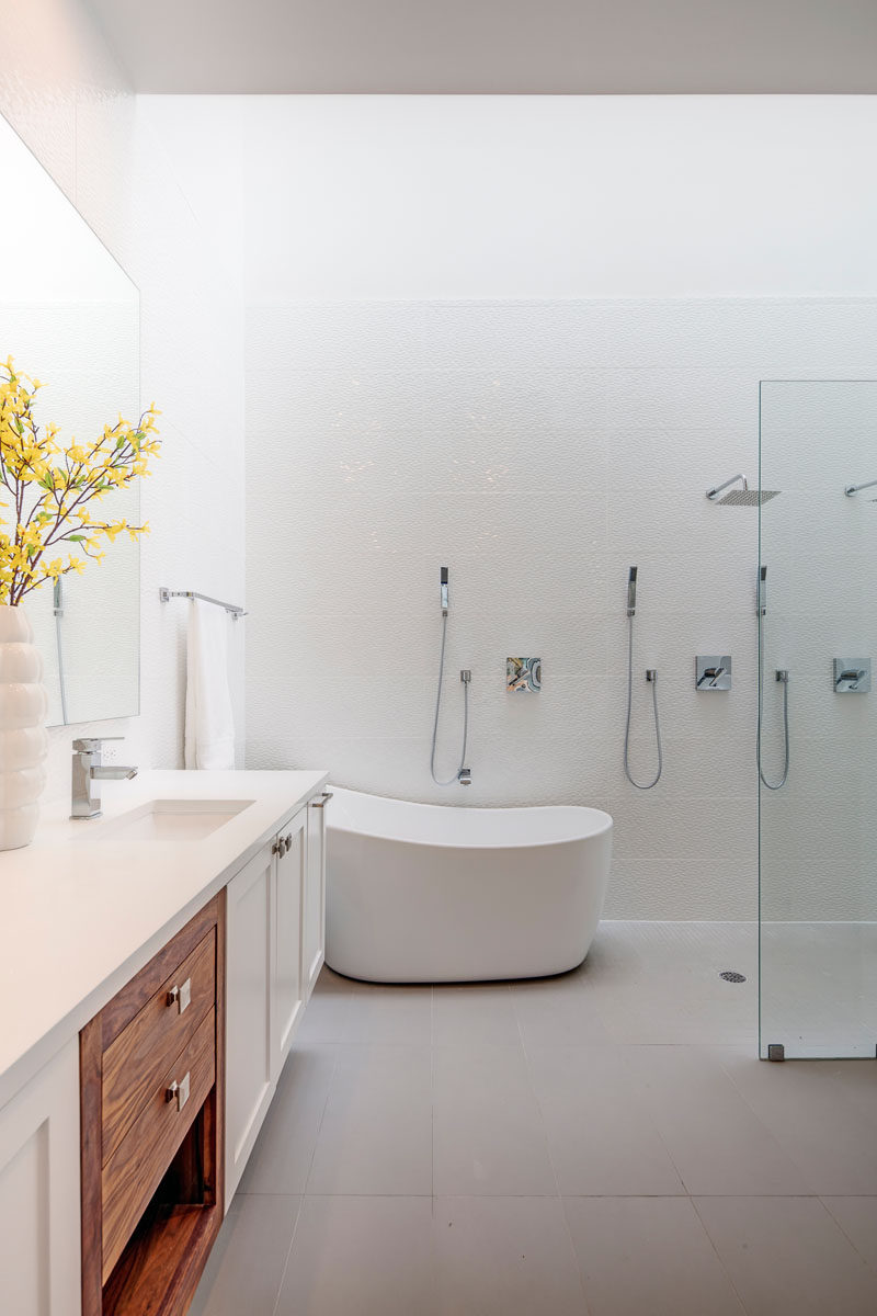 In this modern master bathroom, there's a deep freestanding soaker tub, a dual shower with a glass partition, and a large vanity.