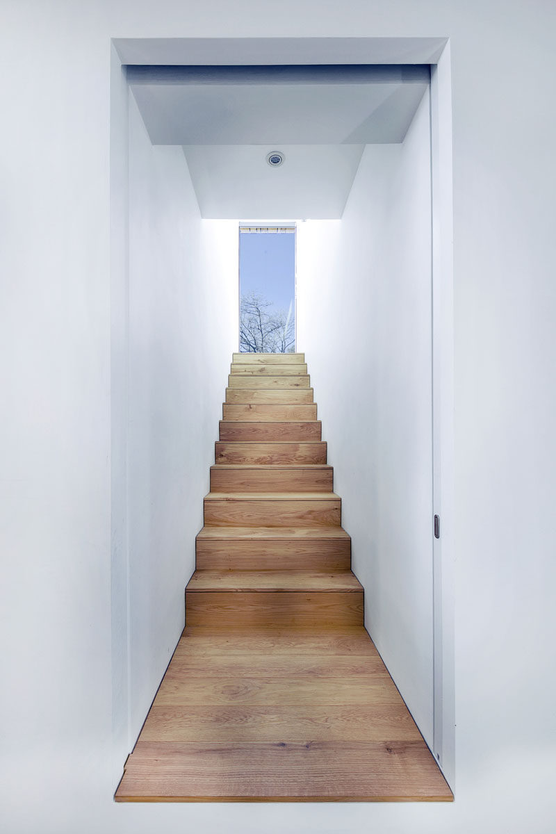 White walls and wooden stairs lead you up to the upper level of this modern holiday home.