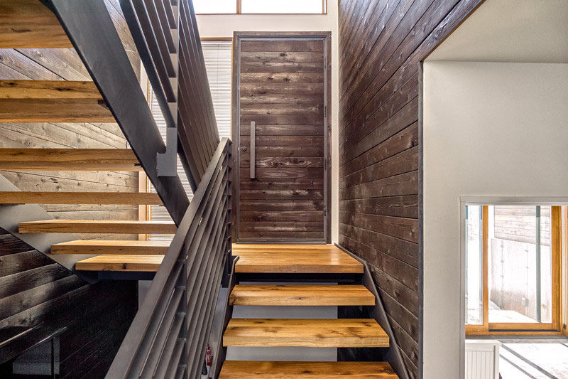 This horizontally paneled dark wood door is made from the same wood that covers the walls of the entry way, creating a unified appearance.