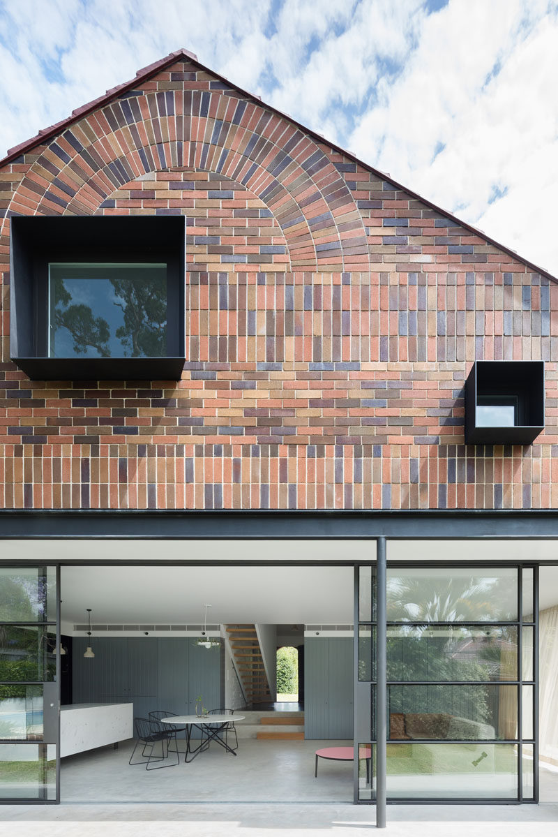 At the back of this renovated home, you can see the two storey gabled roof extension, including the wall of windows on the first level and the brick second storey extension.