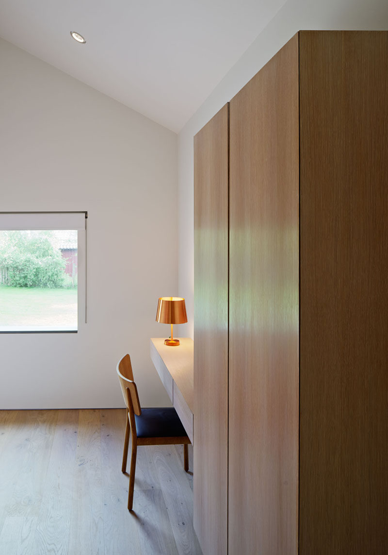 In this modern bedroom, wood cabinets provide storage, and a floating wood desk gives someone a quiet work area.