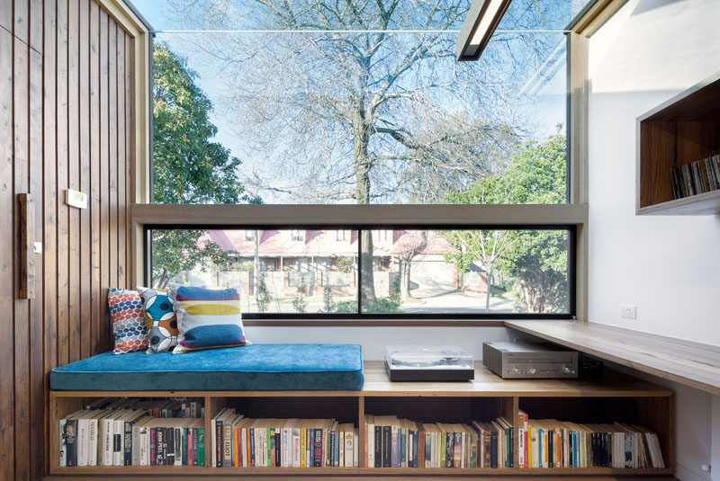 At the very front of this modern house, a built-in reading nook sits beneath a glass ceiling and looks out onto the street. A number of shelving units, including one built into the bench, hold books and music to create the perfect spot to relax and unwind in.