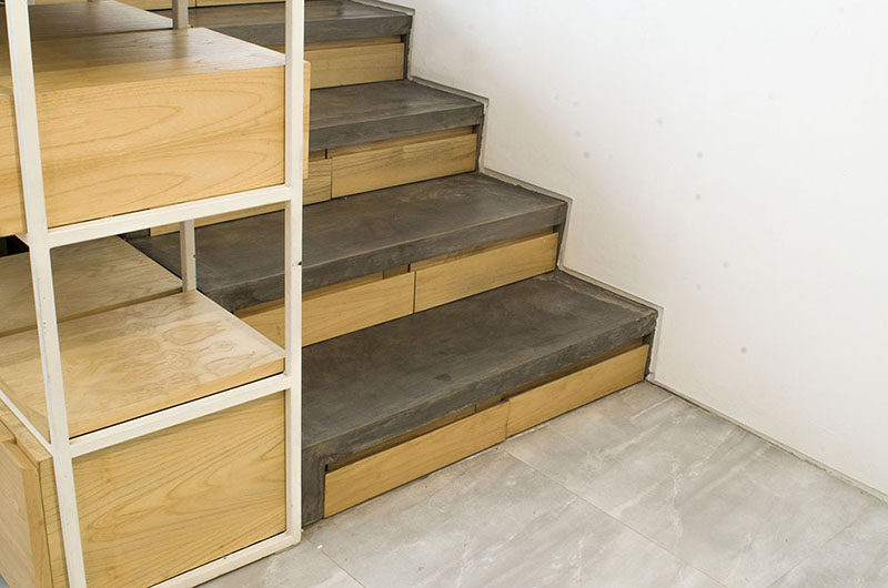 This concrete and wood staircase in a modern Indonesian house, has hidden stair storage within the concrete risers, ideal for bags, jackets and shoe storage