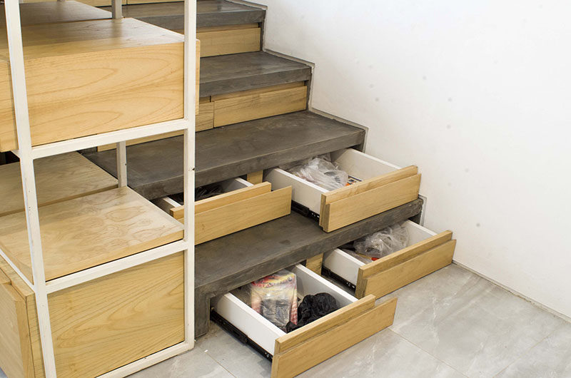This concrete and wood staircase in a modern Indonesian house, has hidden stair storage within the concrete risers, ideal for bags, jackets and shoe storage