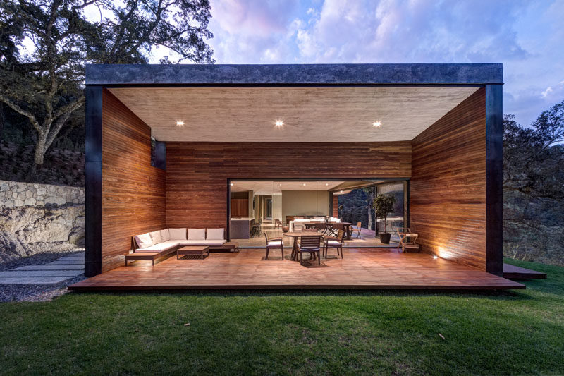 Off to the side of the main living area in this modern house is a large covered outdoor entertaining space. The wood walls surround an additional living and dining area, and protect the area from the elements.