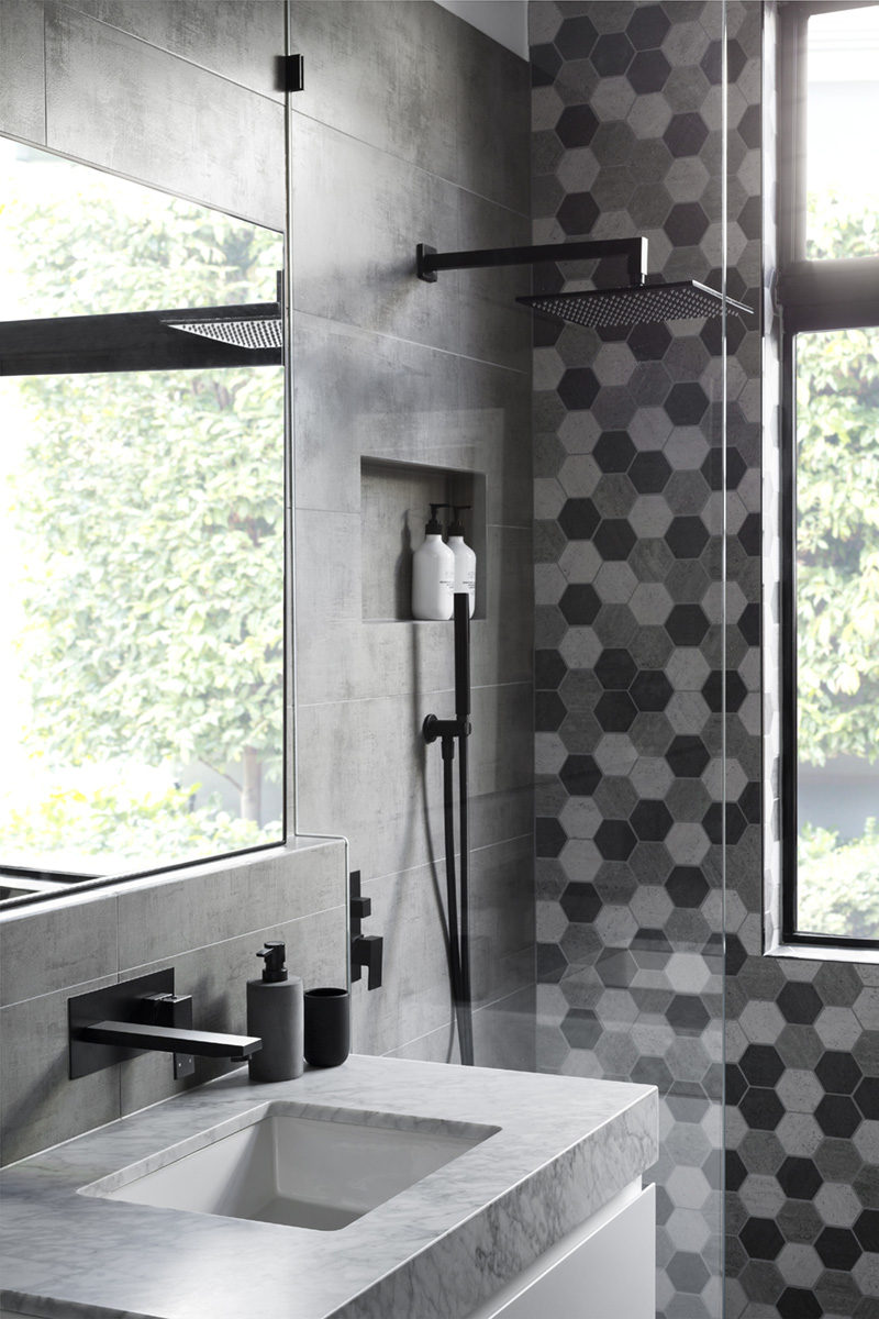 In this modern grey and white bathroom, matte black accents like soap pumps and hardware add a sense of sophistication to the bathroom and shower.