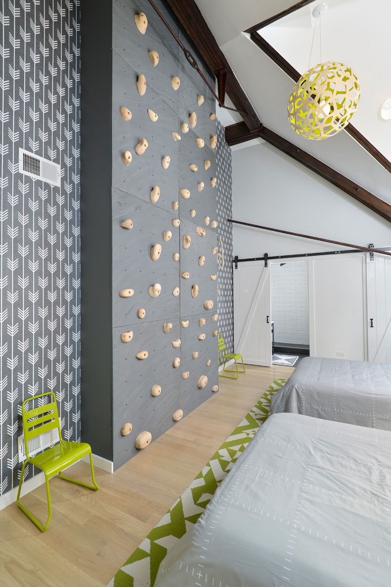 Eight large wood panels covered with rock climbing holds have been installed in this modern bedroom to create a rock climbing wall that can be enjoyed no matter what the weather is doing. #RockClimbingWall #InteriorRockClimbingWalls #InteriorDesign