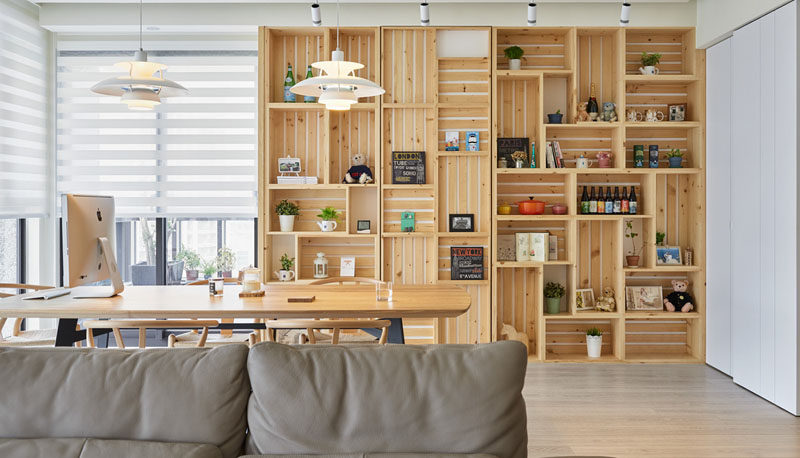 This modern apartment interior features a wall of wood crates that become a bookshelf and add storage to the room