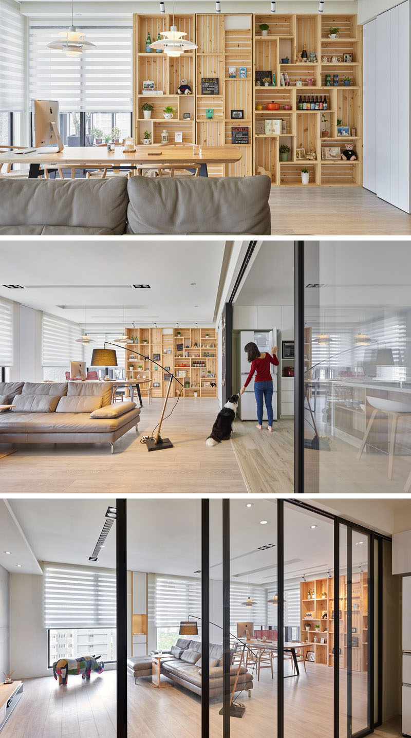 This modern apartment interior features a wall of wood crates that become a bookshelf and add storage to the room