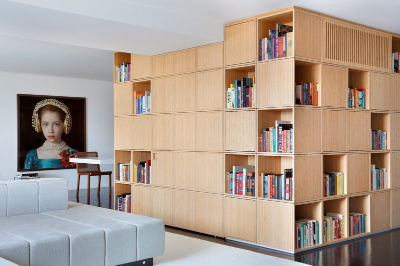 In this modern apartment, the entryway is concealed within the wood bookshelf.