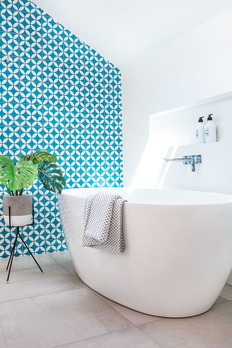 This modern blue and white bathroom has a built-in shelf above the freestanding bathtub to keep all the necessities within arms reach.