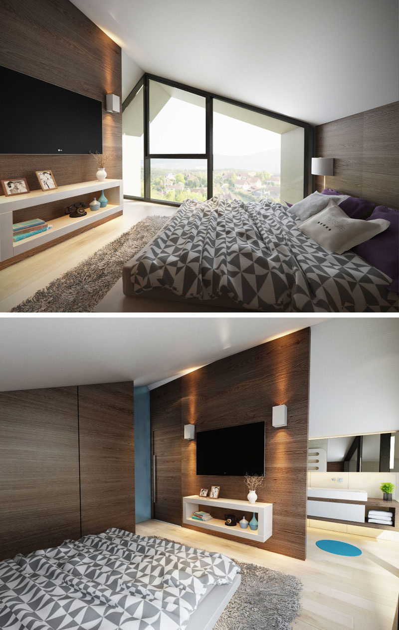 The windows in this modern bedroom follow the line of the roof, and dark wood accent walls have been used behind the bed and on the opposite wall to create a contrast to the white ceiling and light wood floors. Behind the wall with the tv is an ensuite bathroom.