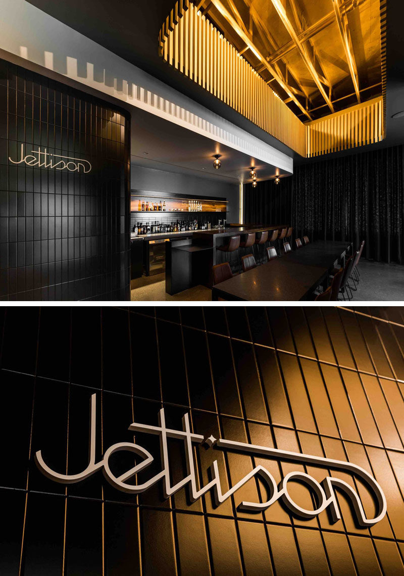 This modern and luxurious cocktail bar has a rich walnut bar with dark grey walls, brown leather seats, a black curtain on the back wall and painted gold touches to create a speakeasy atmosphere.