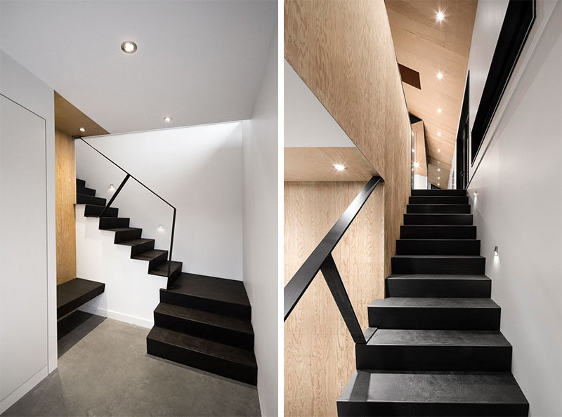 Light wood and white walls contrast these black stairs leading up from the basement to the main level of the home.