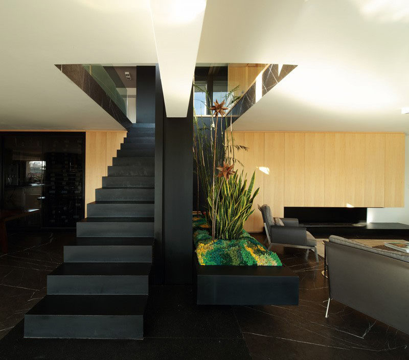 This black steel staircase divides the living and dining spaces in this modern apartment that was created by combining two separate units into one.