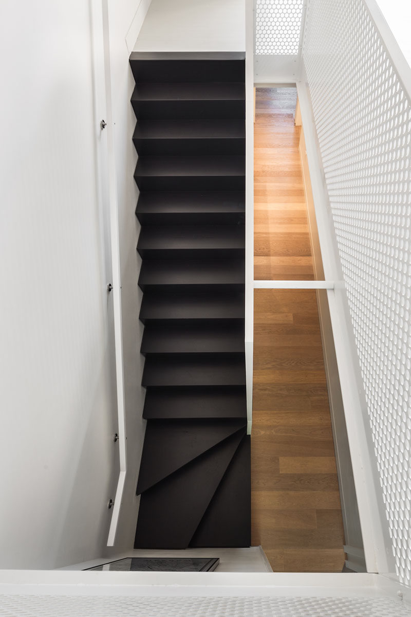 These black modern stairs are surrounded by white walls and handrails, as well as light wood flooring making it stand out and become a focal point in the interior.