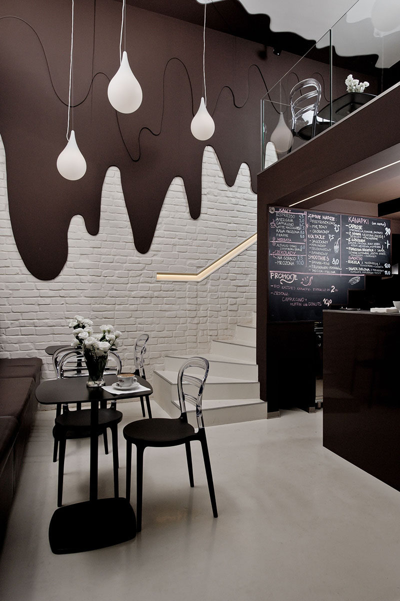 This modern chocolate shop and cafe design with two levels, has walls with 'dripping dark chocolate' and white pendant lights representing 'milk drops'.