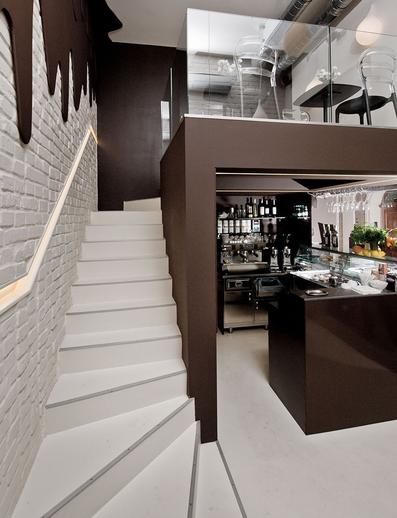 This modern chocolate shop and cafe design with two levels, has walls with 'dripping dark chocolate' and white pendant lights representing 'milk drops'.