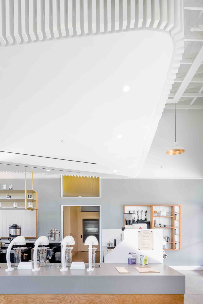 Inside this modern coffee shop, the interior is bright white and the high ceilings help to create a sense of openness. A 'cloud' that's positioned above the service bar draws your eye upwards and creates a focal point in the space, while at the same time, it hides the mechanical system.