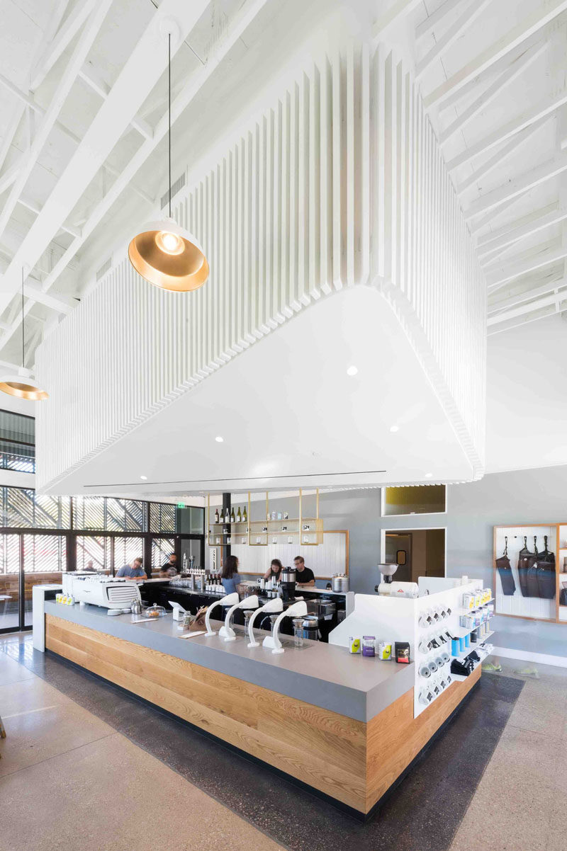 Inside this modern coffee shop, the interior is bright white and the high ceilings help to create a sense of openness. A 'cloud' that's positioned above the service bar draws your eye upwards and creates a focal point in the space, while at the same time, it hides the mechanical system.