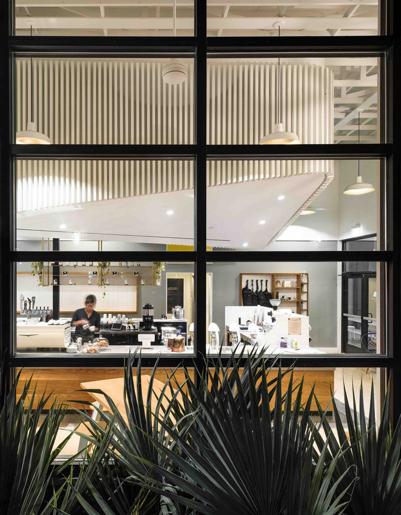 This modern coffee shop has dramatic black framed windows and a bright white interior.