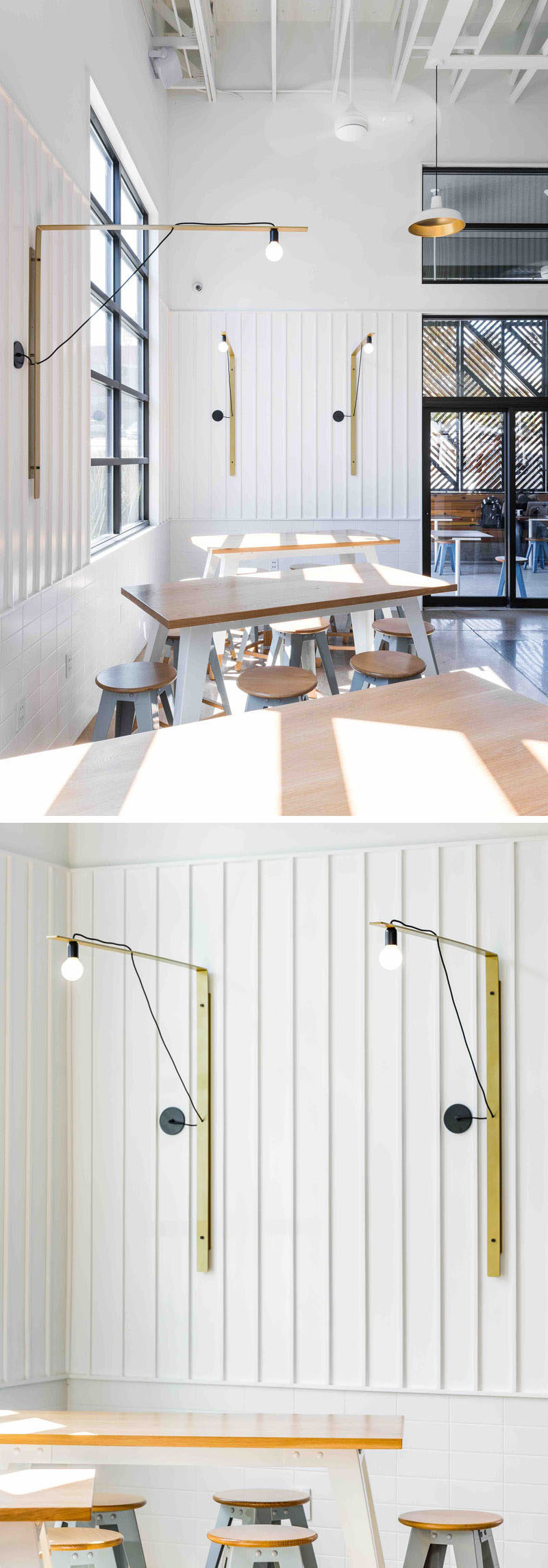 In this modern coffee shop, bar height tables and stools are positioned by the window, with simple metallic gold light fixtures adorning the walls.