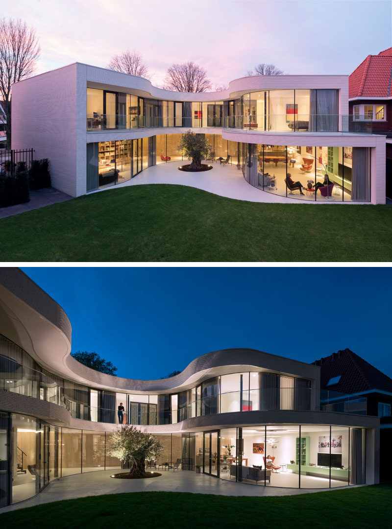 This modern house full of curved glass windows opens up to the backyard and curves around a mature olive tree.