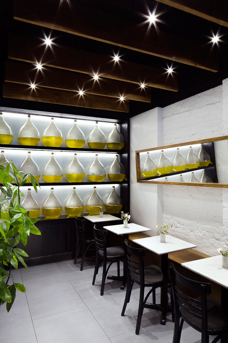 At the back of this modern restaurant is a more formal dining area featuring a wall of oils that adds authenticity to the Greek restaurant and a horizontally placed mirror that helps the small space feel larger and more open.
