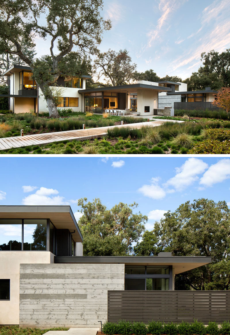 In the backyard of this modern house, the yard has been landscaped to preserve the existing trees and foliage, and has extra greenery added to make the yard more inviting. The concrete, steel, and wood, also visible at the back of the home, contrasts the natural landscape and makes the house stand out with it's modern appearance.