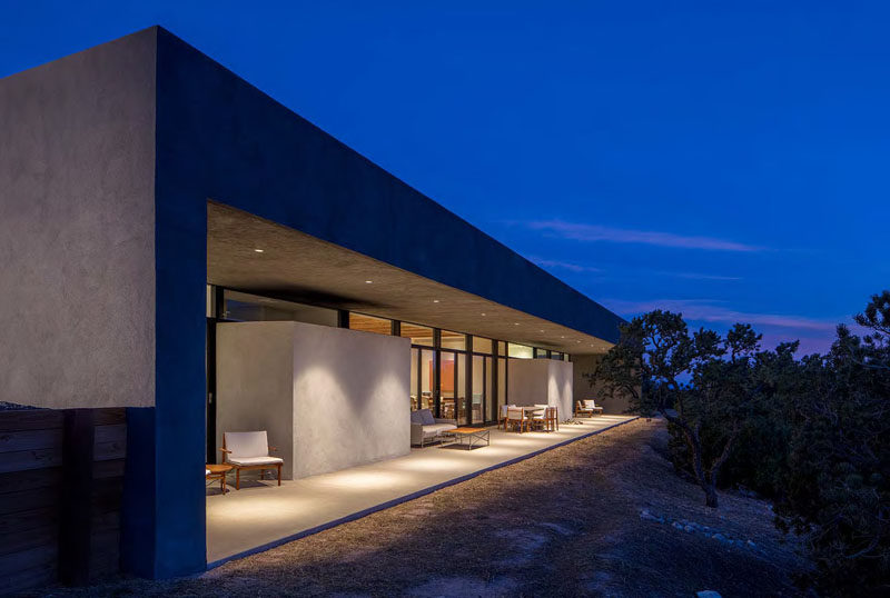 Outside the rear of this modern house is a porch that runs the length of the house. The outdoor porches are shaded by a cantilevered roof, provide a space to relax out of the sun.