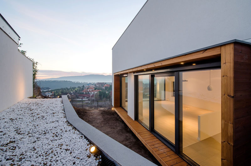 On the side of this modern house, a wood frame surrounds the windows and breaks up the all white exterior walls.