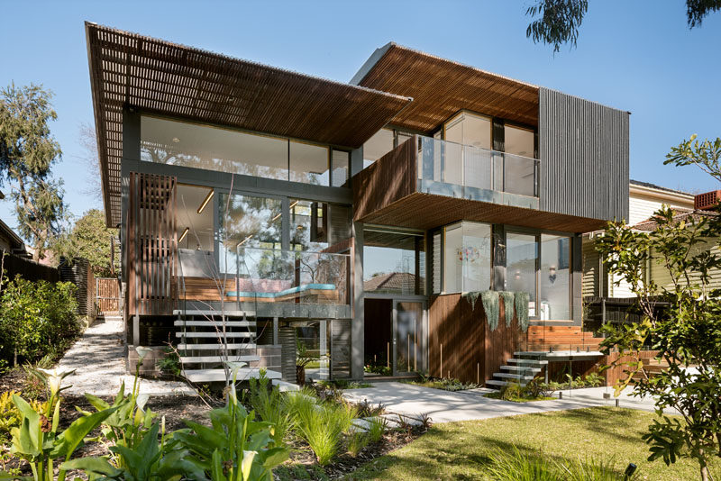 This multi-level modern house has large windows covering much of the back exterior, while steel and wood cover any non-glass surface.