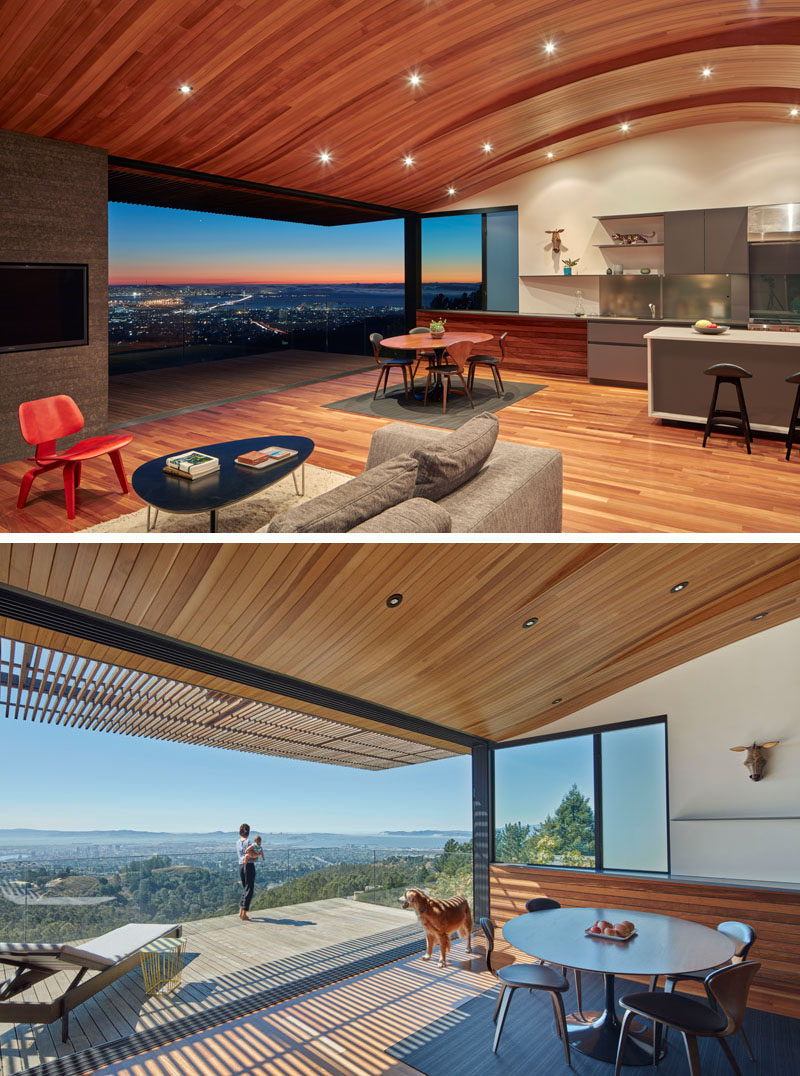 Inside this modern house, an unexpected feature of the interior is the wood ceiling that has curves that echo the contours of the hillside that the house sits on. The main floor which is home to the kitchen, dining room and living room, opens up to a balcony with glass railings. 