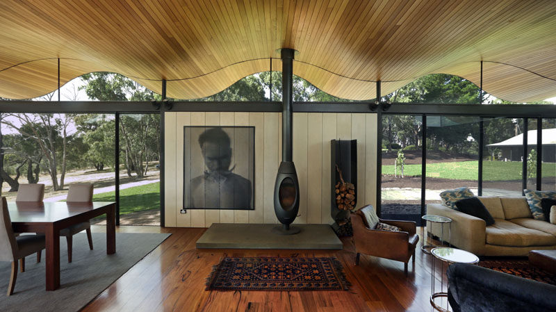 Inside this modern house, the ceiling is made up of wood curves, while floor-to-ceiling windows match the roof line.