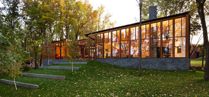 This modern house covered in wood, metal and stone, has floor-to-ceiling windows that follow the line of the roof to take advantage of the lakeside views and let in as much natural light as possible.