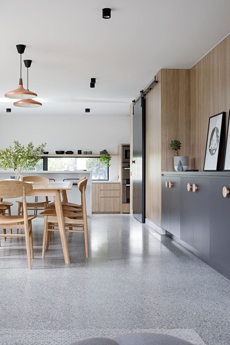 In this modern house, a matte black sliding barn door hides the pantry that sits between the dining room and the kitchen.