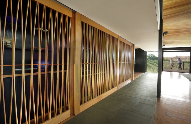 In this modern house, an artistic wood sliding door creates a screen that partially conceals an art collection confined to a small nook as well as a bar area.