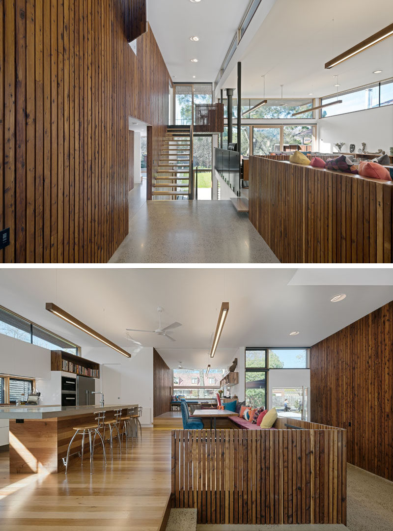 In this modern house, dark wood paneling has been used on the walls and on some of the kitchen shelving while white walls reflect the light coming in through the many windows on the floor.